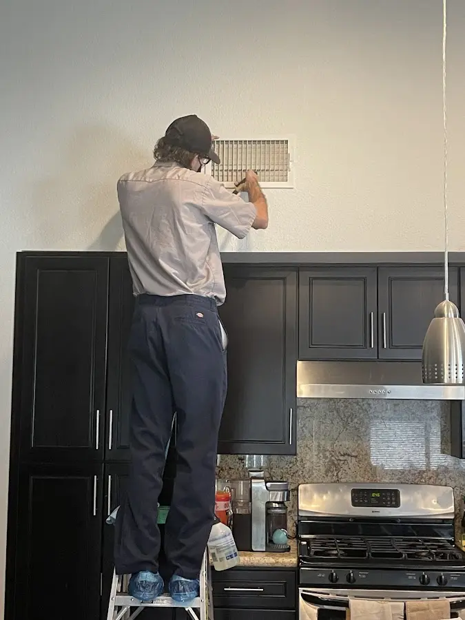 Technician inspecting an air vent during HVAC service in Oakhurst